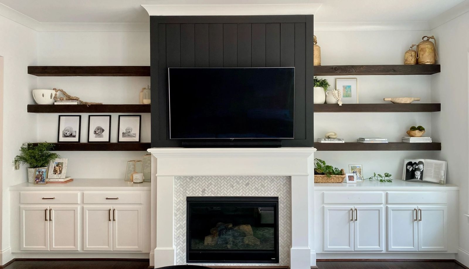 Fireplace and media wall with custom white cabinetry, dark wood shelves and brass handles