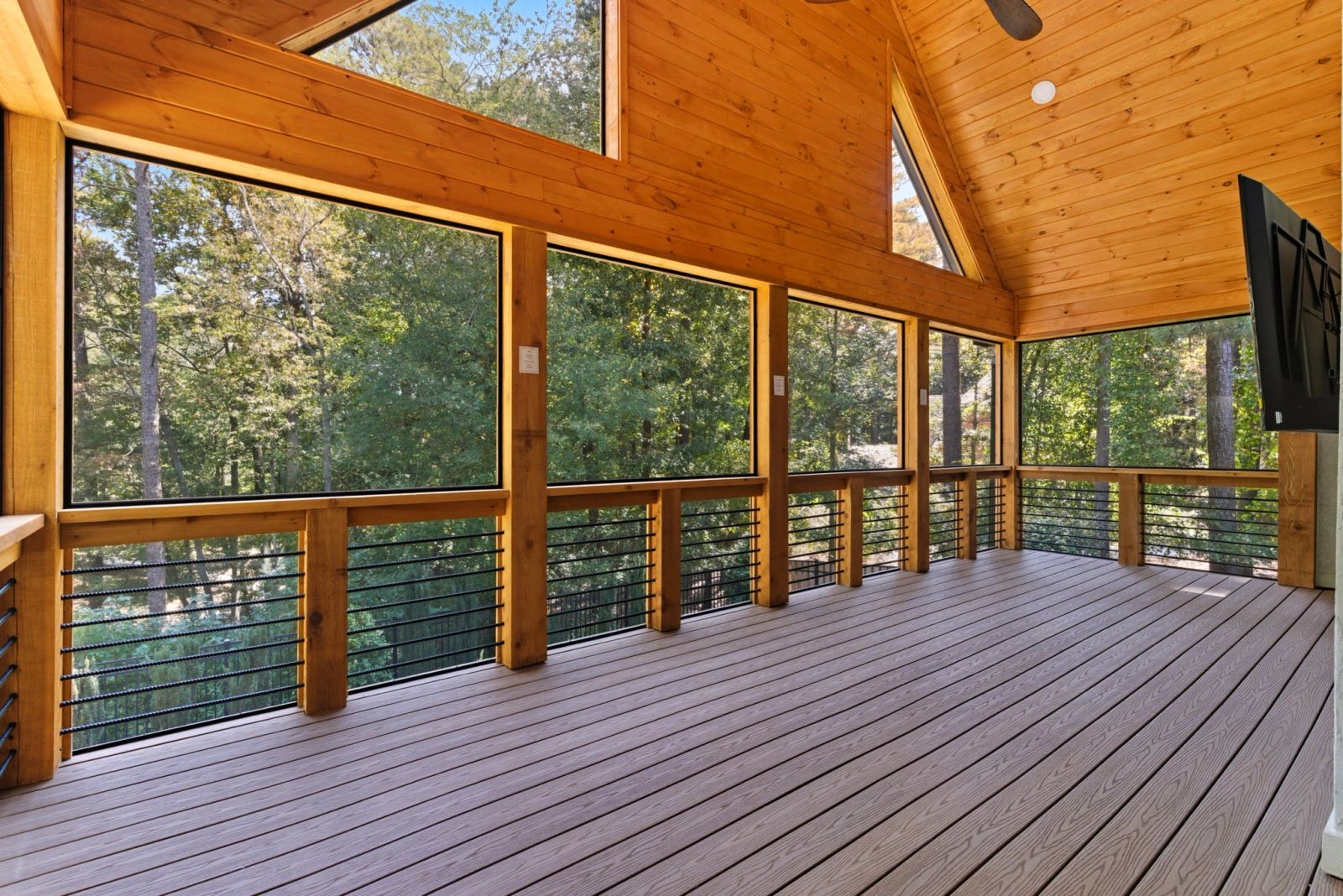 Covered outdoor living space with a soaring timber ceiling and wooded views